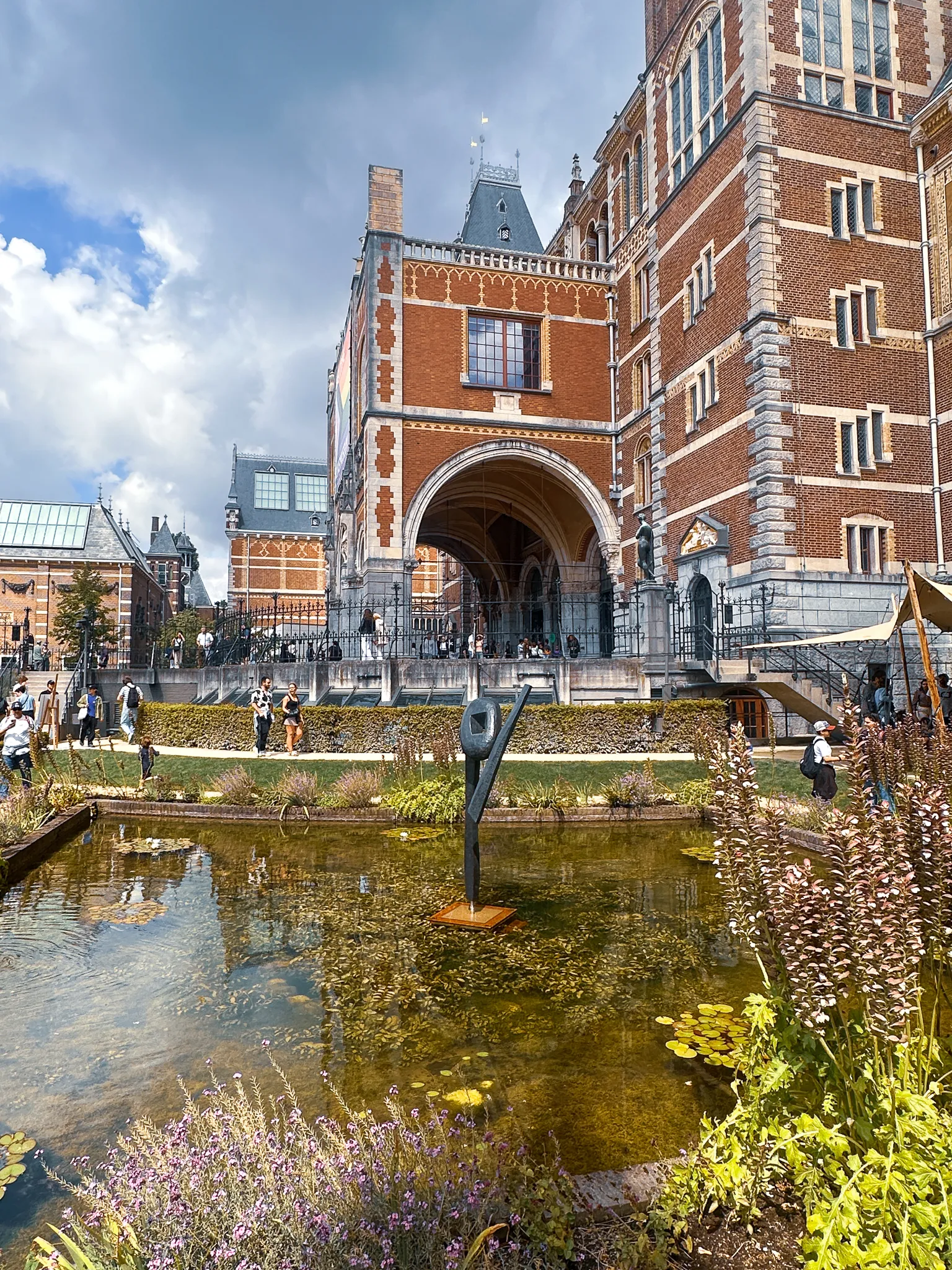 The Rijksmuseum's red brick and stone above its garden, the arched passage cut straight through the middle, a slim bronze figure standing in a shallow lily pond and lavender and grasses in front