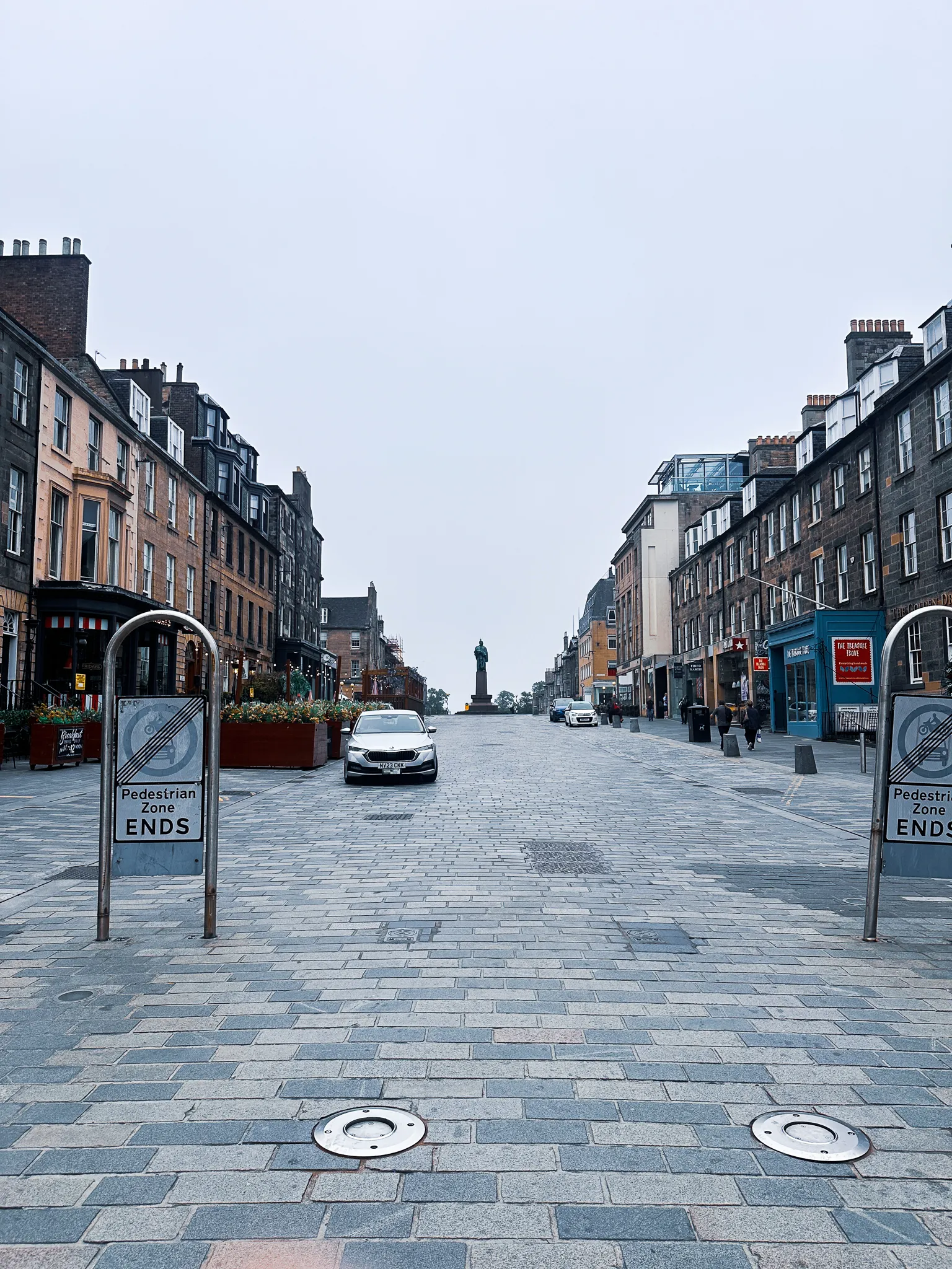 George Street on Sunday morning, almost empty - pedestrian-zone signs, one parked car and a statue silhouetted where the street crests