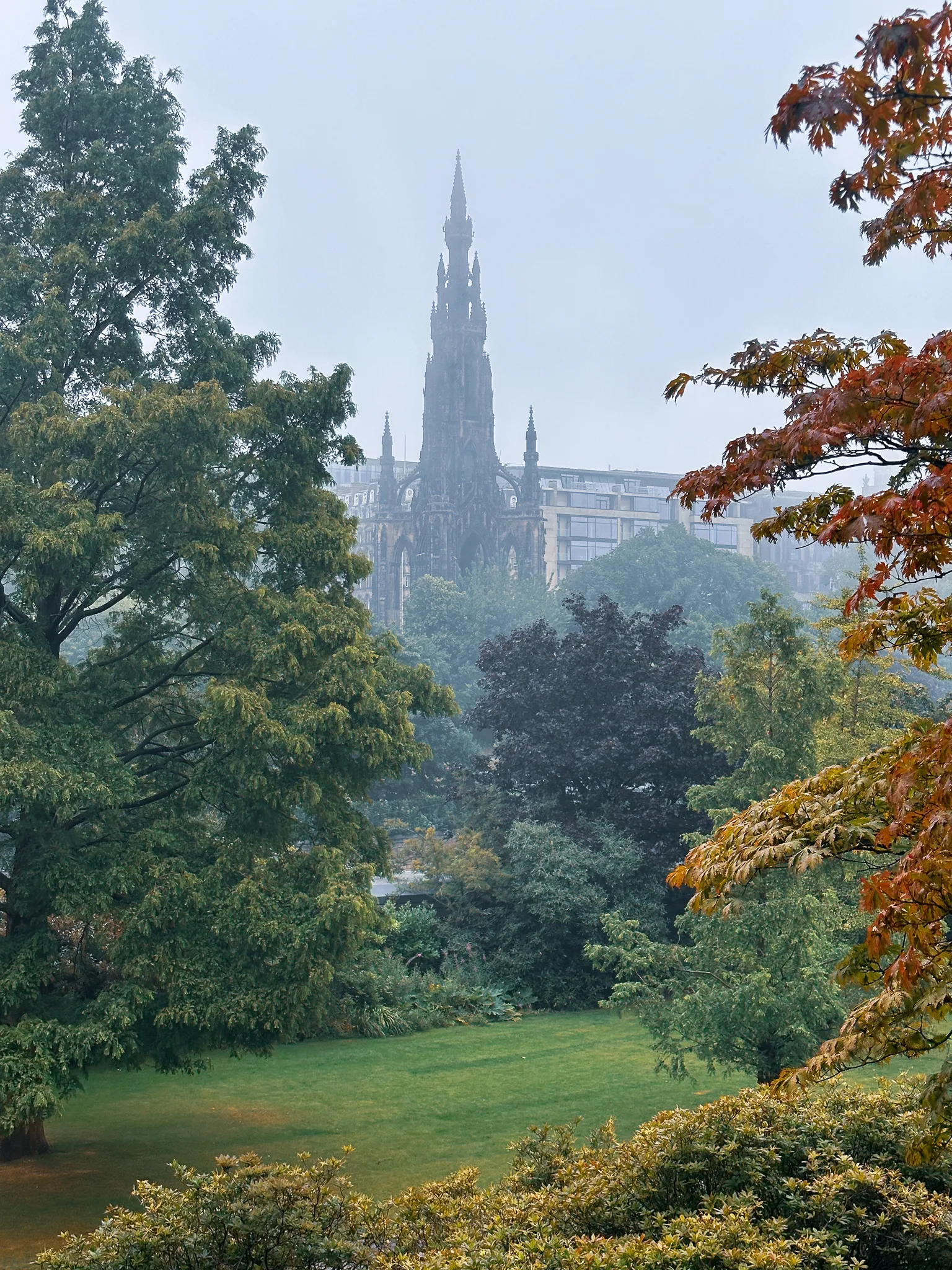 The Scott Monument's blackened Gothic spire rising out of the gardens' trees into the mist, a lawn opening below it