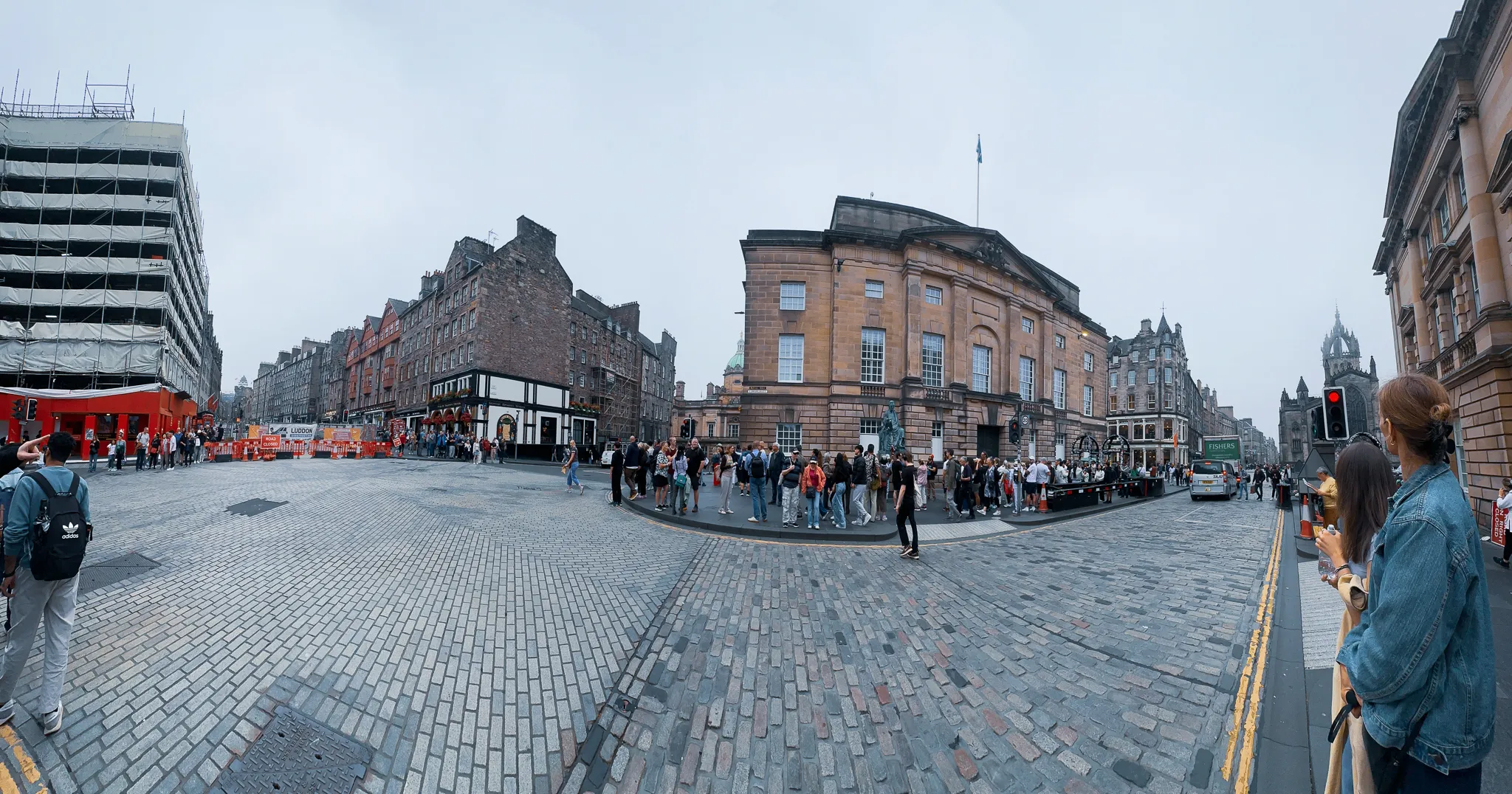 A panorama at the top of the Mile - the High Court with David Hume seated in bronze out front, a tour gathering at the corner and St Giles' crown down the street