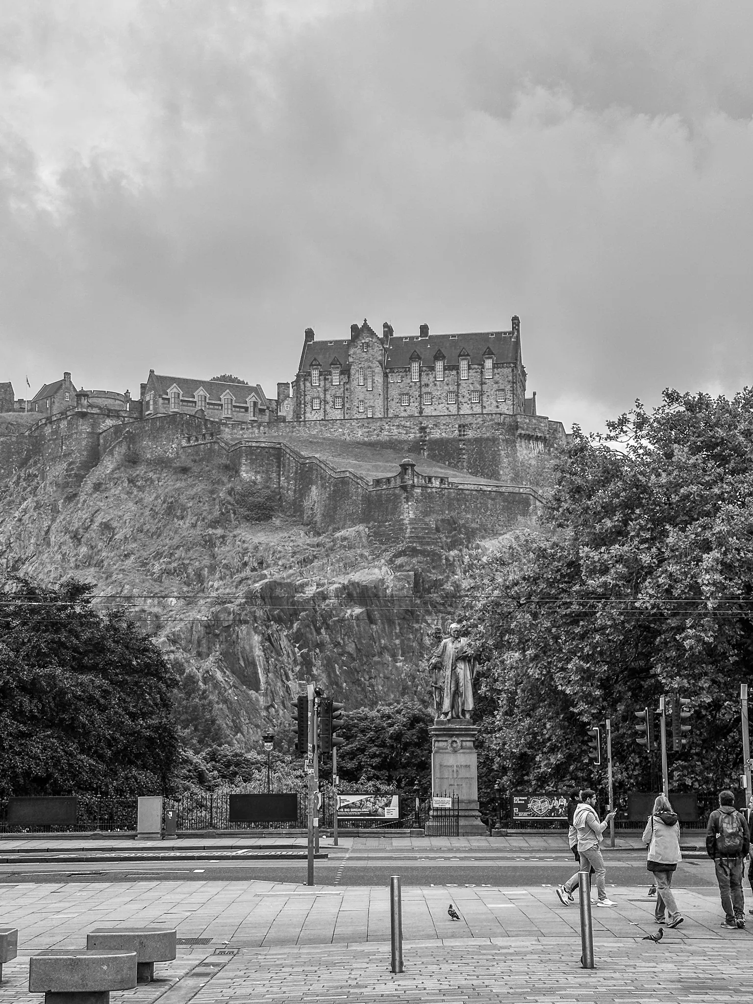 The castle in black and white from Princes Street, the Thomas Guthrie statue below and a pigeon working the pavement