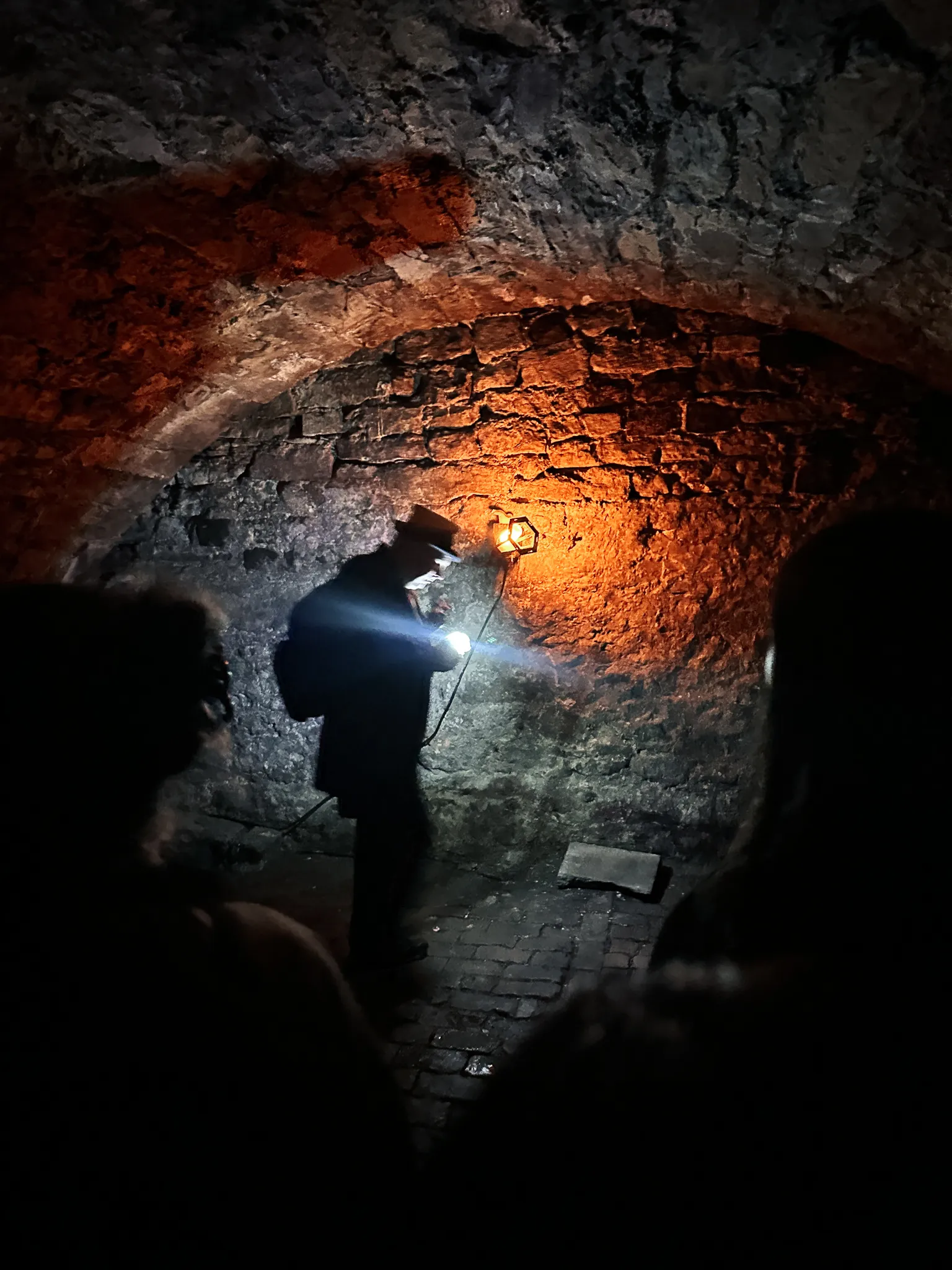 Down in the vaults - the guide in a top hat lit by one lantern against the bare stone arch, the group no more than silhouettes