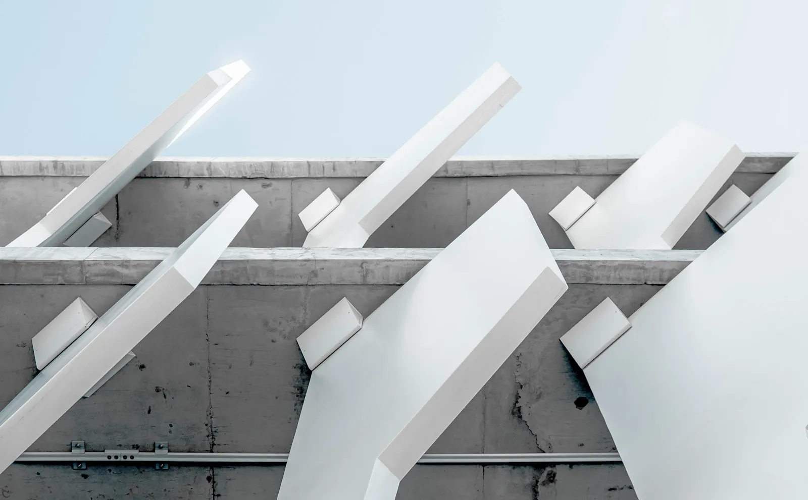 White angled beams projecting from a concrete wall against a pale sky