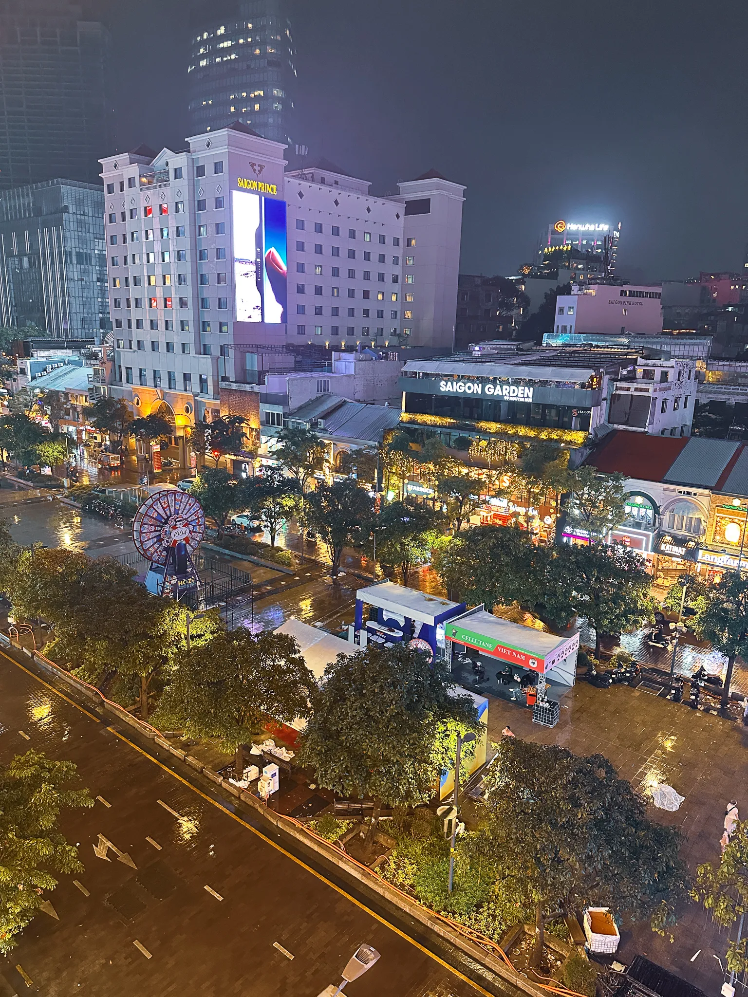 Nguyen Hue walking street from a balcony on a rainy night, wet paving throwing the hotel lights back up