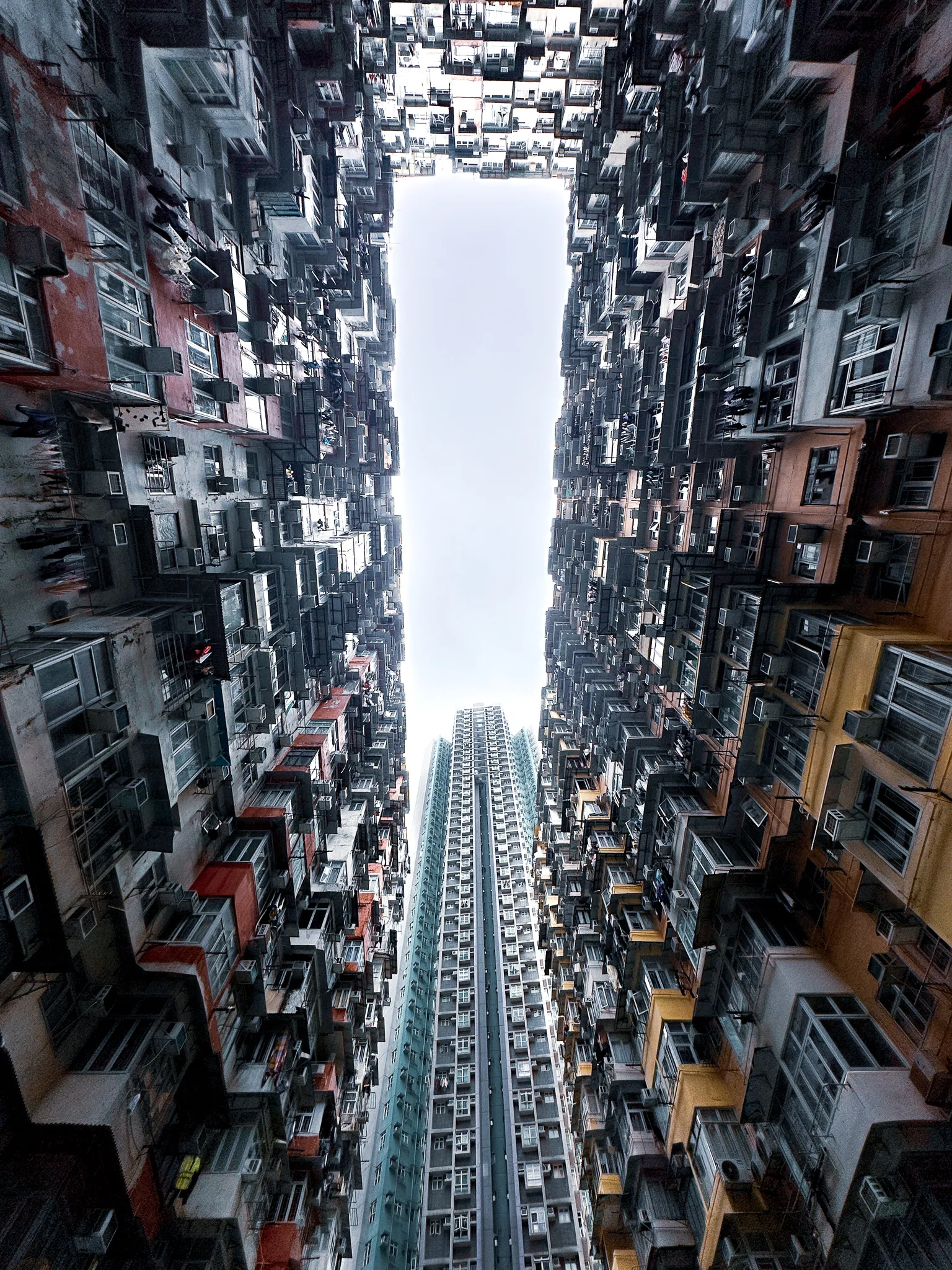 Straight up between two walls of flats, air-conditioners and drying rails repeating away to a narrow slot of white sky