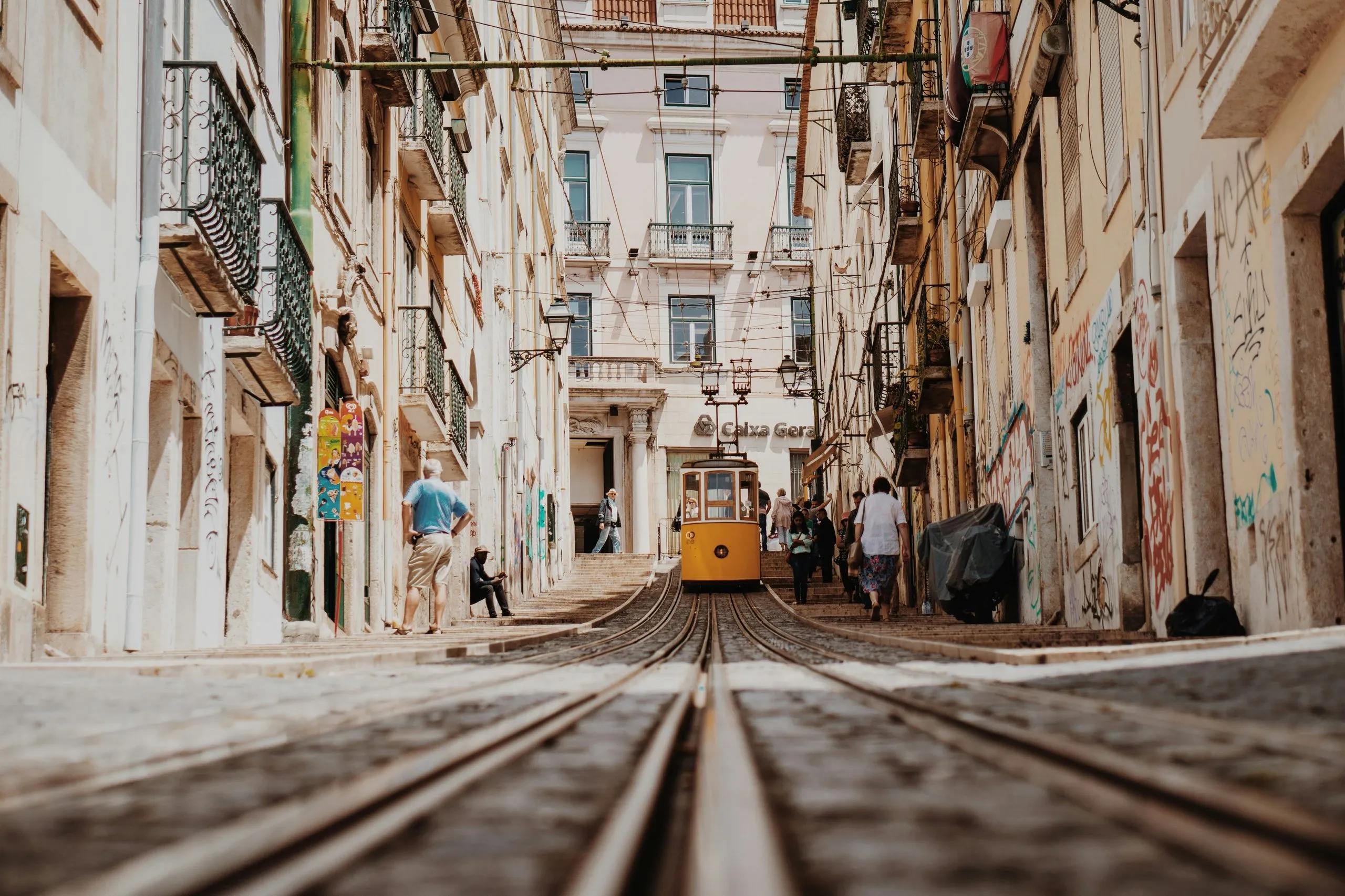 A tram climbing a narrow street of graffitied walls, the rails running straight out of the bottom of the frame