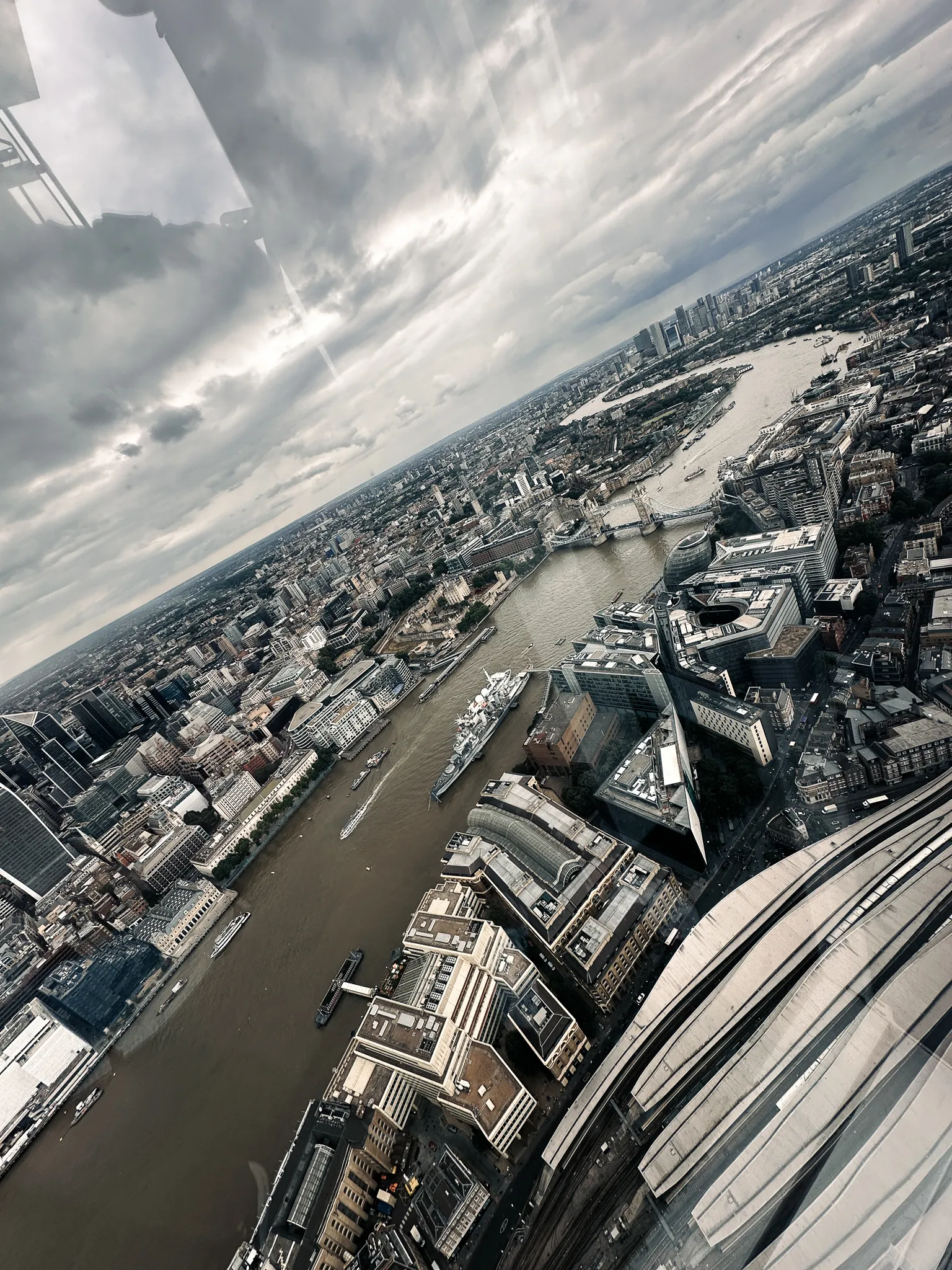 Straight down the river to the east - Tower Bridge small in the distance, HMS Belfast a white shape on the water, the glass roof of London Bridge station in the bottom corner and the window's reflections at the top