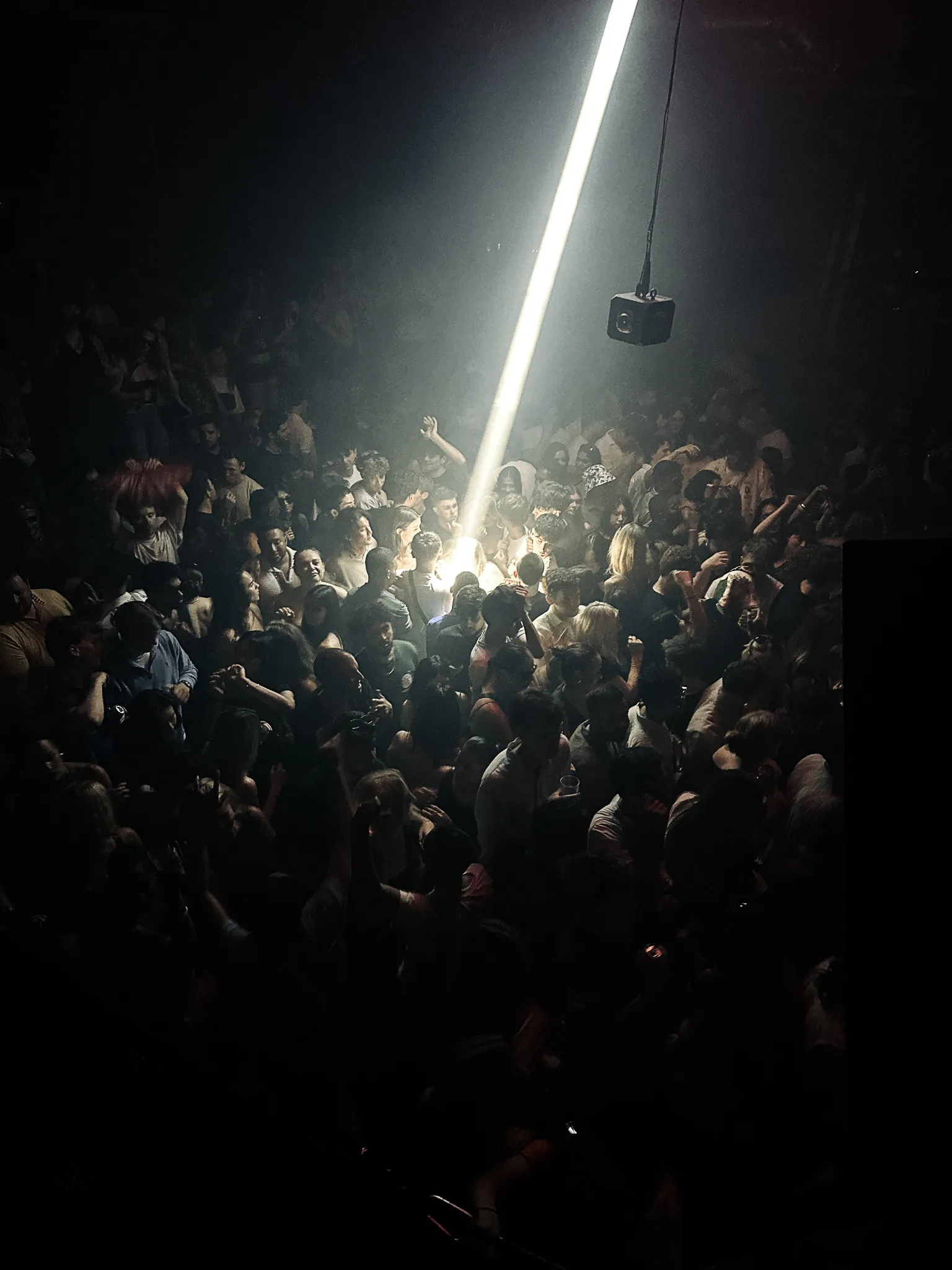 One hard beam of light dropped into the middle of the crowd with hands up in it, the rest of the room in the dark