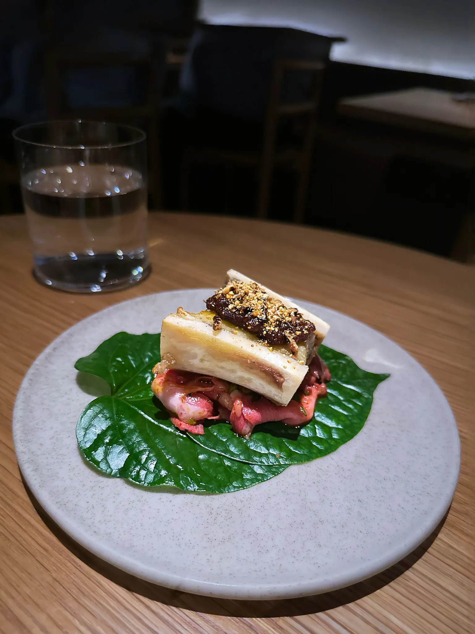 A slab of marrow under a crumb crust over pink beef on a betel leaf