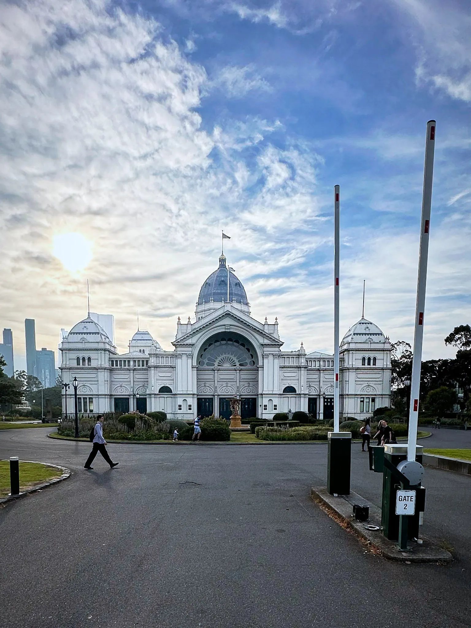 The Royal Exhibition Building's dome across the Carlton Gardens forecourt, sun breaking through cloud