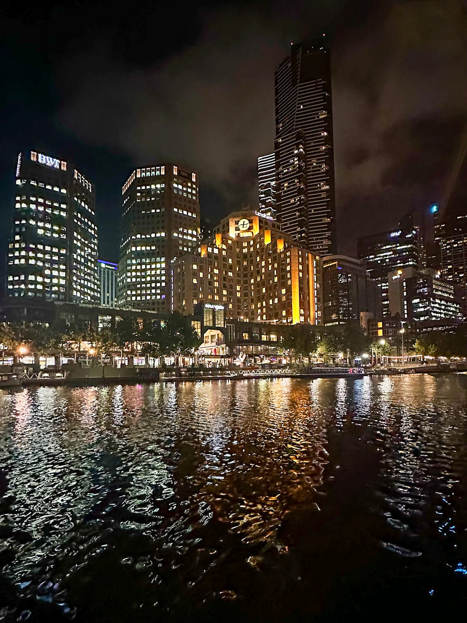Southbank's towers lit gold and white at night, reflected in the Yarra