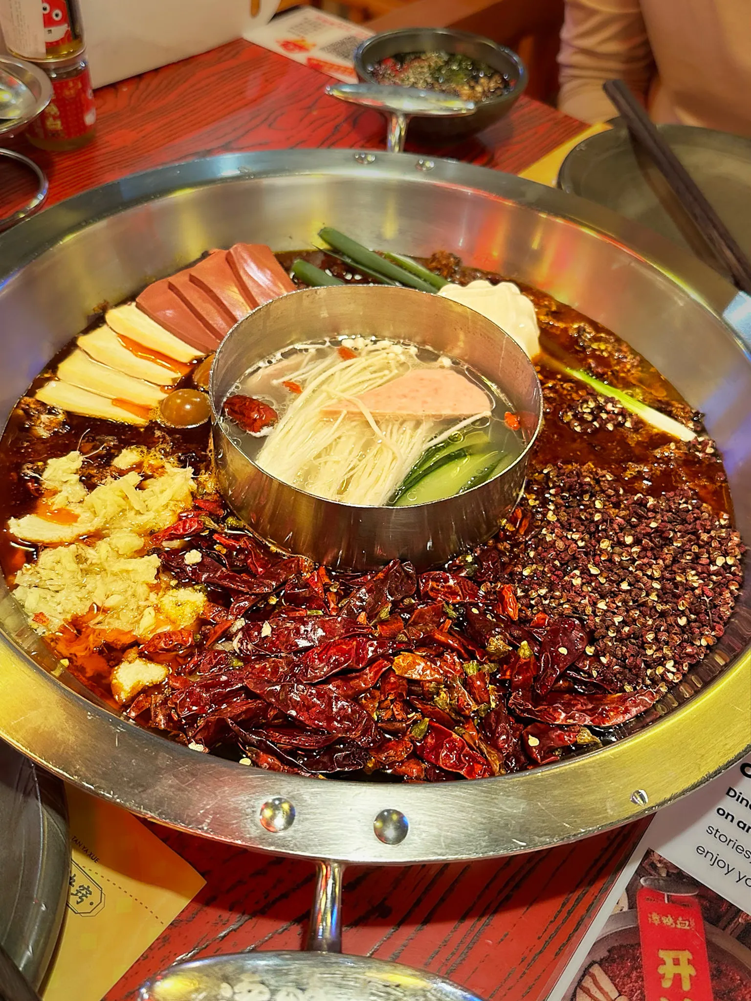 A divided hotpot, one half stacked with dried chillies, the other a clear broth