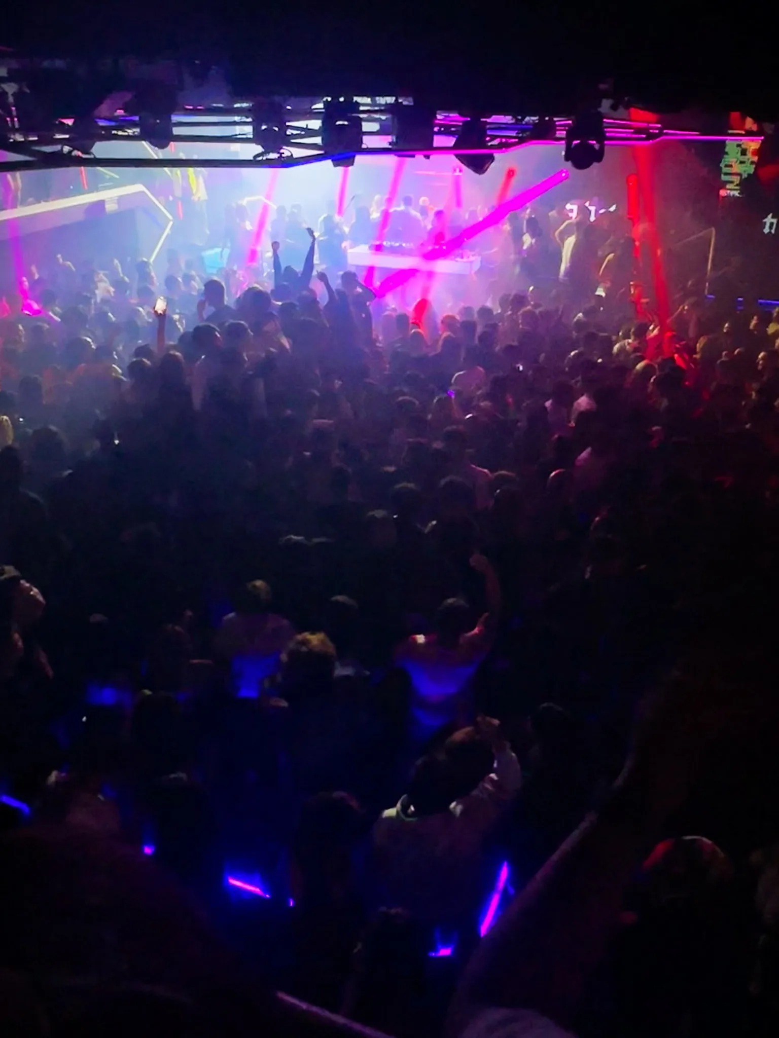 A packed club under red and blue lasers, hands in the air