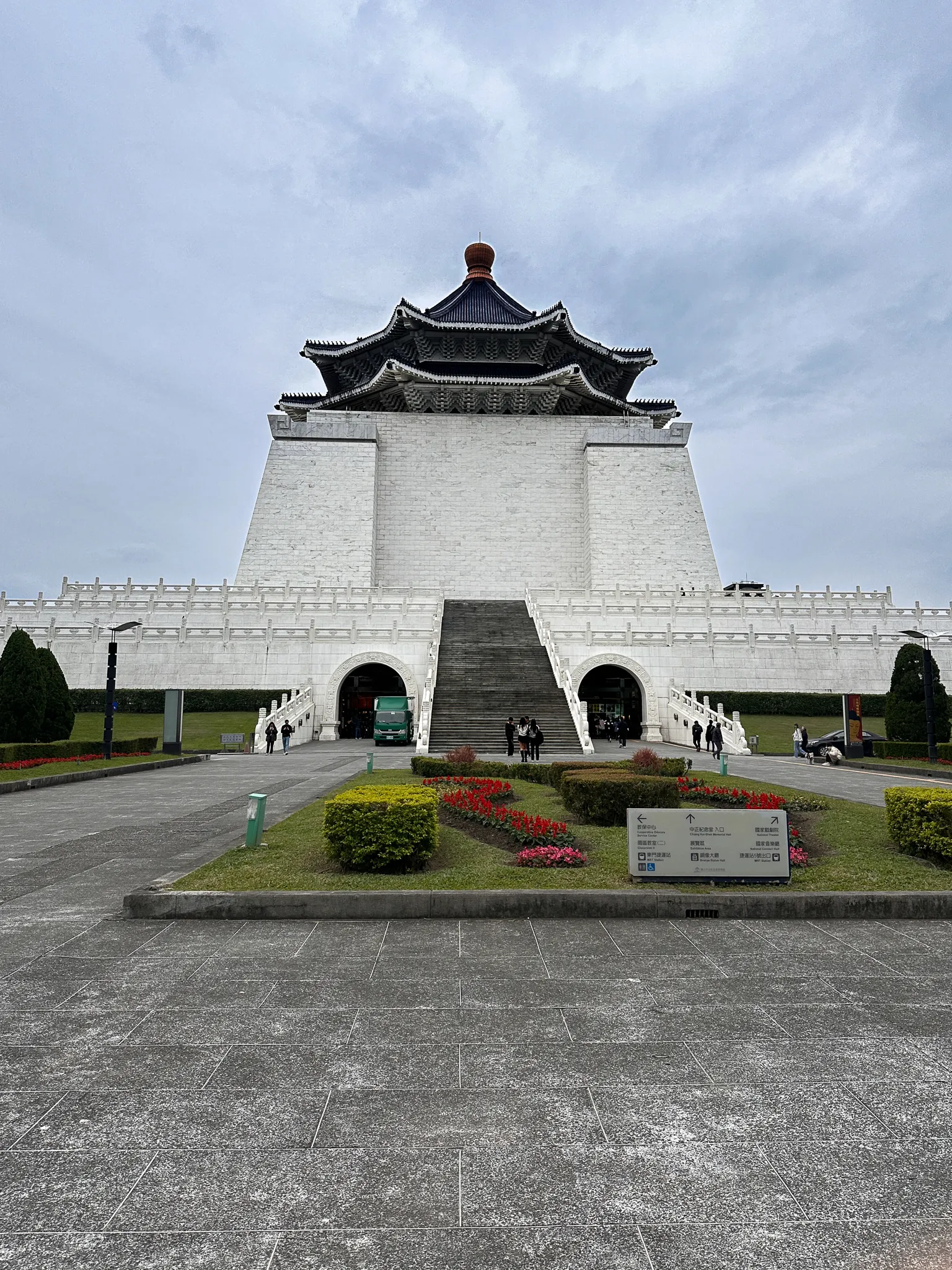 The Chiang Kai-shek Memorial Hall straight on across the plaza, white walls under a blue octagonal roof, red and pink flowerbeds and clipped hedges laid out in front
